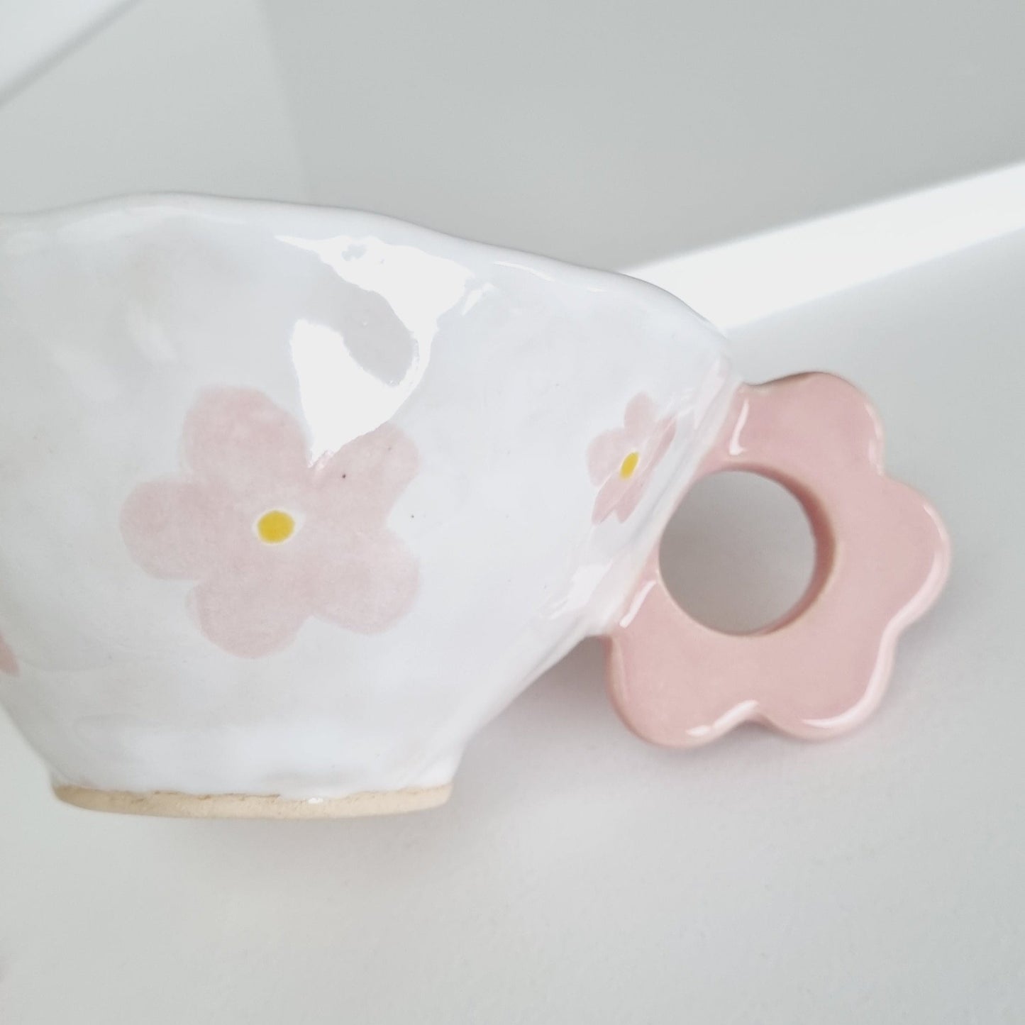 Pink flower handle on handmade ceramic mug.