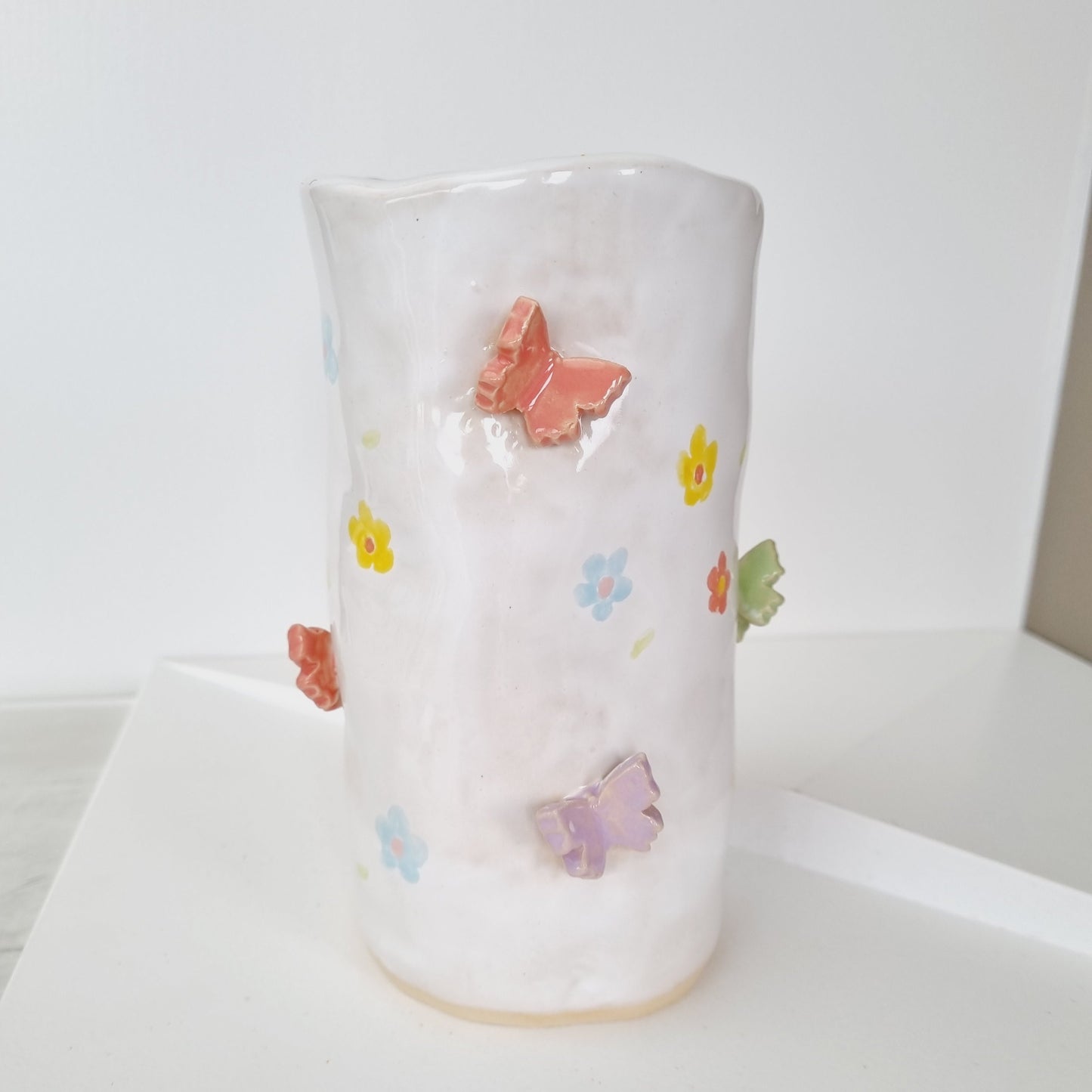 unique handmade whimsical white vase, decorated with colorful 3D butterflies. Handpainted daisies