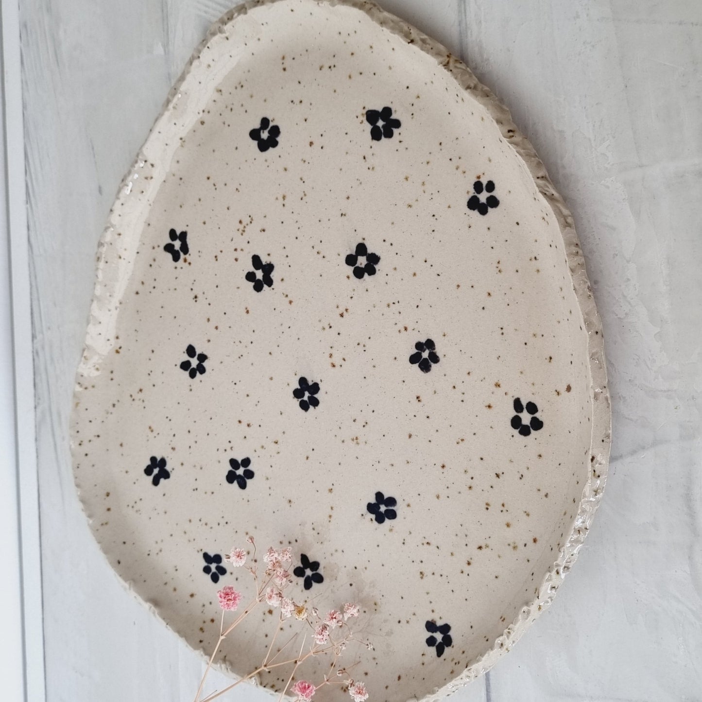 Organic plate made from speckled clay. Black daisies