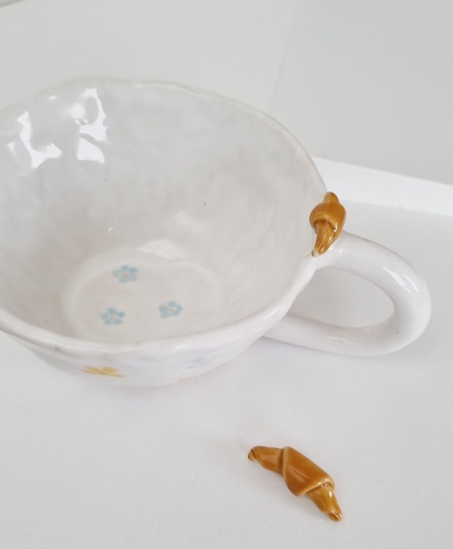 Sweet mug with croissant on the rim