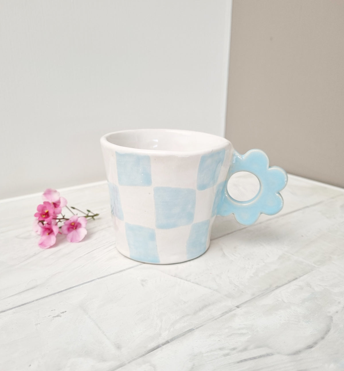 Hübsche Tasse mit blauem Karomuster und blumenförmigem Henkel