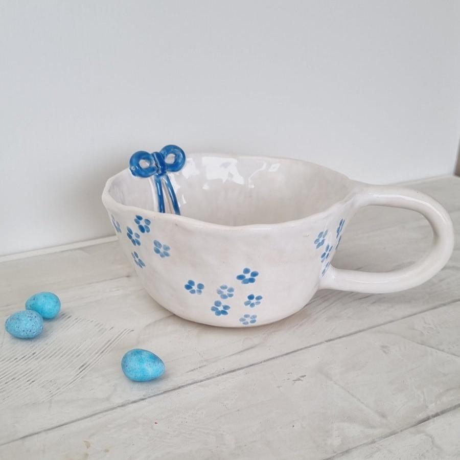 Cute  ceramic handmade mug with blue bow on the rim. Handpainted with blue daisies