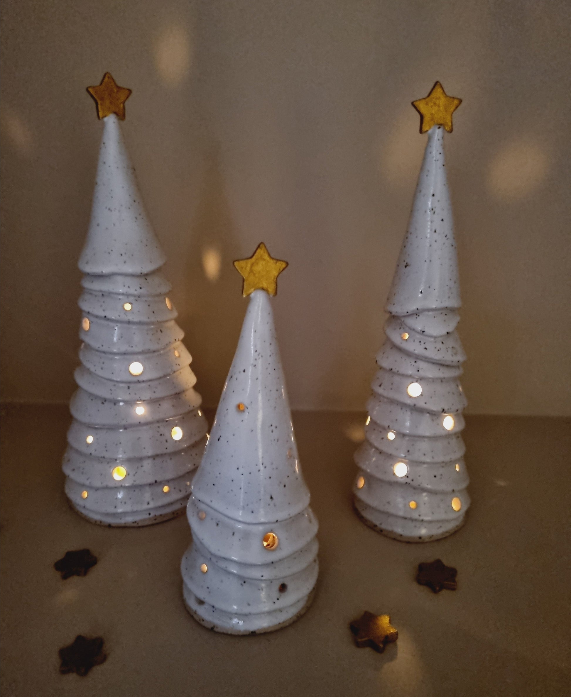 White speckled ceramic Christmas trees, luminaries, style ribbon. decorated with a golden star