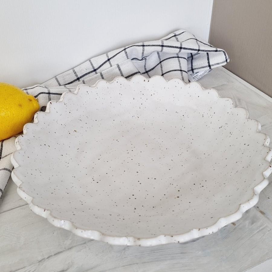 Speckled white plate with scalloped rim