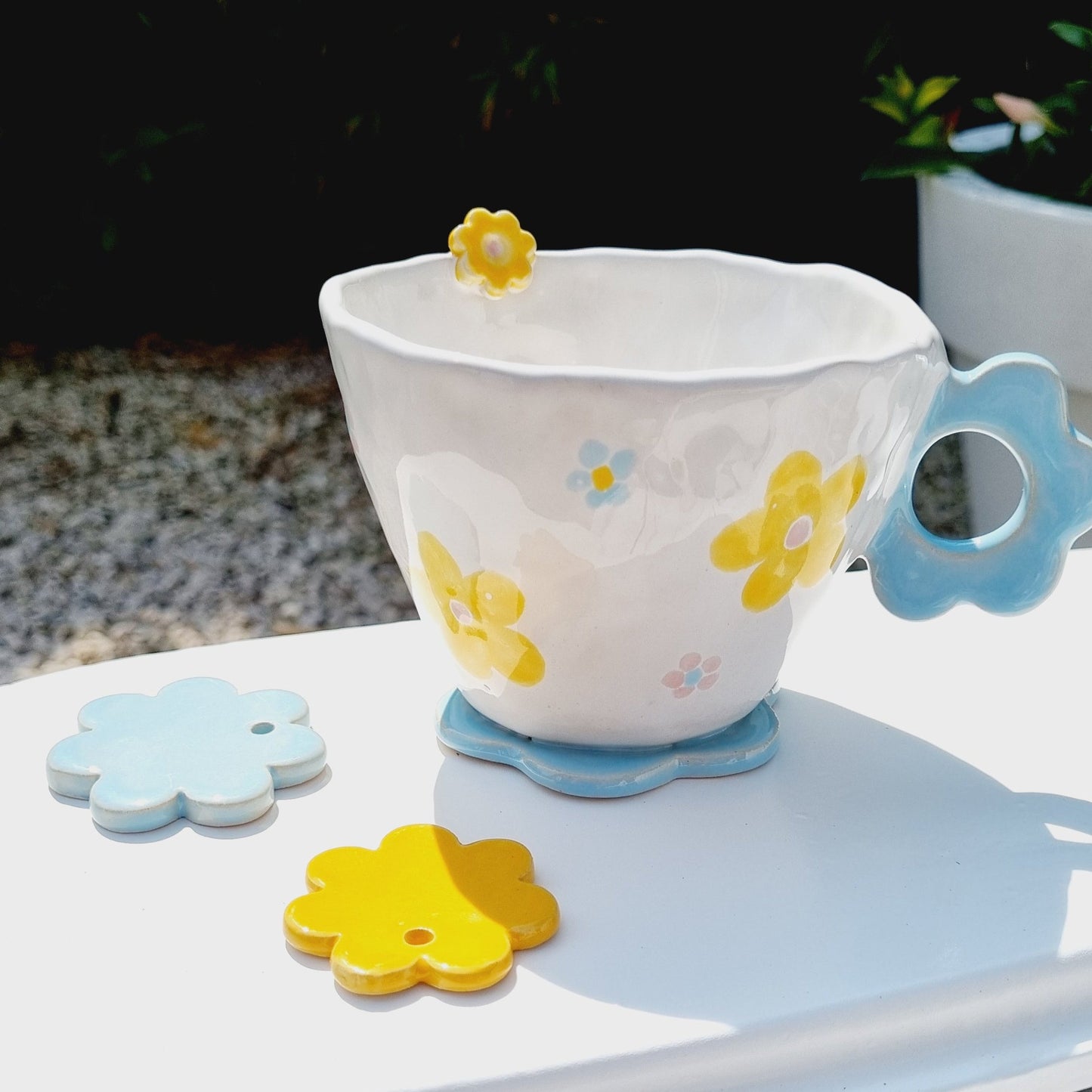 Handpinched mug with a flower handle. handpainted with blue and yellow flowers