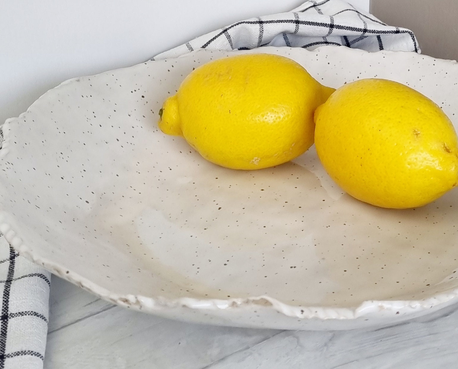 Large white centerpiece bowl with black speckles and uneven rim