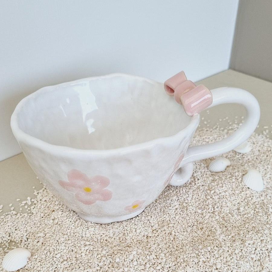 White handpinched coffee up with a pink bow on the handle. decorated with handpainted pink flowers